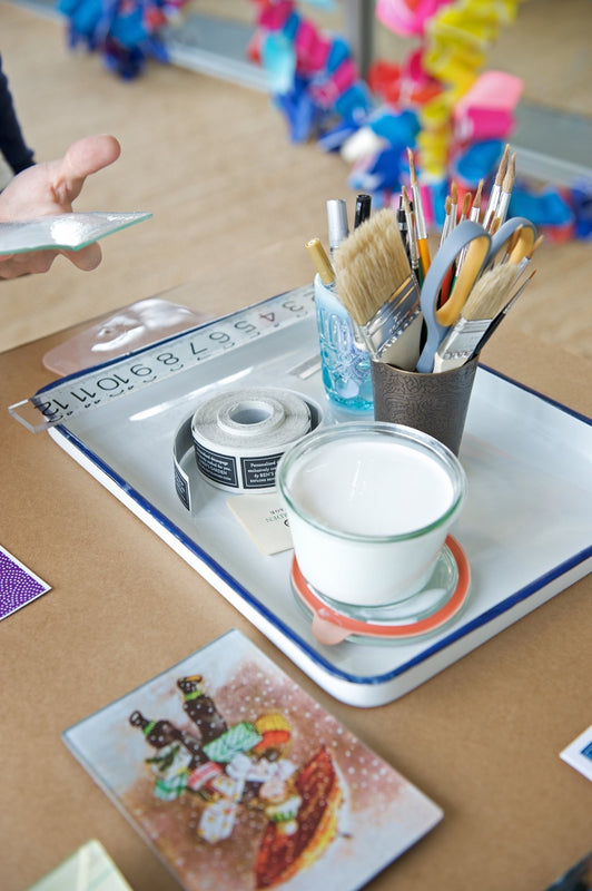 Brushes, glass, and finishing tools on the Ben's Garden studio table