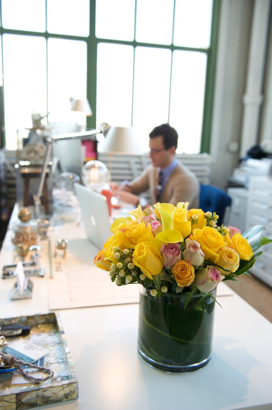 Ben Busko at work behind a vase of yellow roses